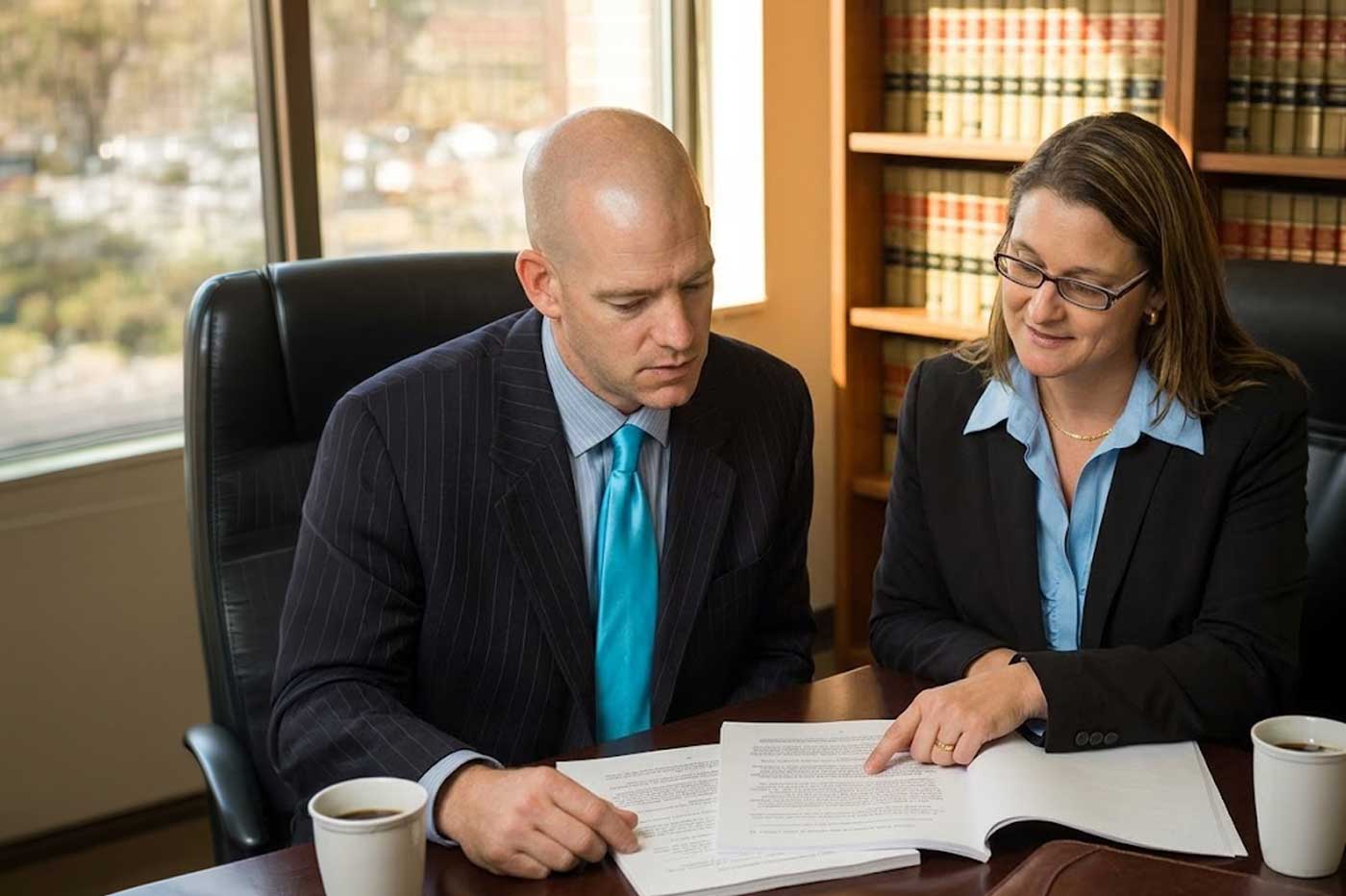 Todd Mays and Leah Rotenberg reviewing case documents at conference table with law books in background